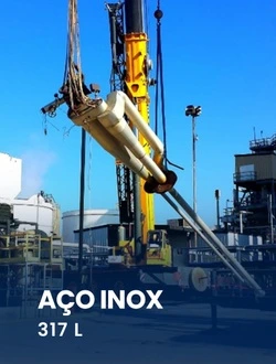 Canteiro de obras industrial com guindaste içando tubos de aço inox 317L para construção de estrutura resistente a ataques químicos.
